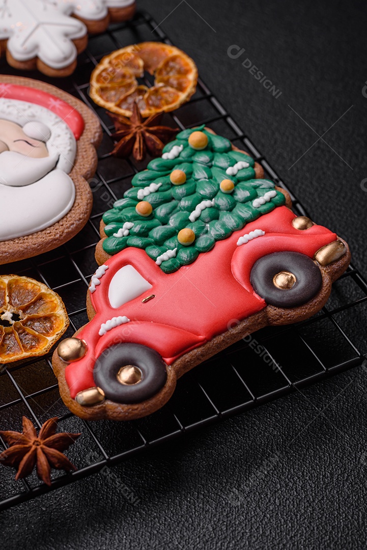 Biscoitos de gengibre frescos e deliciosos de Natal ou ano novo com padrão temático de cor brilhante em fundo escuro de concreto