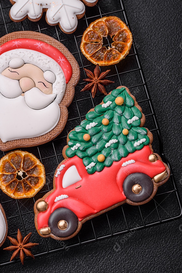 Biscoitos de gengibre frescos e deliciosos de Natal ou ano novo com padrão temático de cor brilhante em fundo escuro de concreto