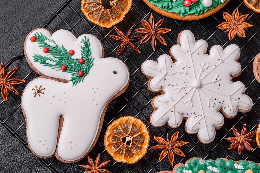 Biscoitos de gengibre frescos e deliciosos de Natal ou ano novo com padrão temático de cor brilhante em fundo escuro de concreto