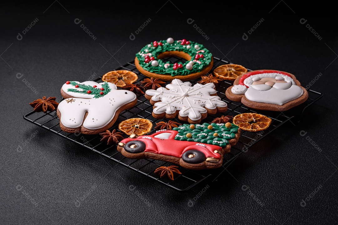 Biscoitos de gengibre frescos e deliciosos de Natal ou ano novo com padrão temático de cor brilhante em fundo escuro de concreto