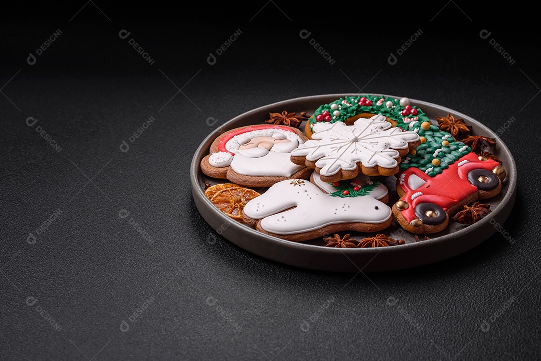 Biscoitos de gengibre frescos e deliciosos de Natal ou ano novo com padrão temático de cor brilhante em fundo escuro de concreto