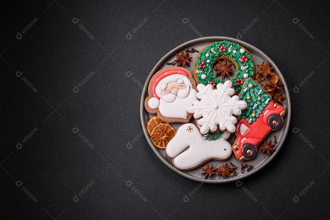 Biscoitos de gengibre frescos e deliciosos de Natal ou ano novo com padrão temático de cor brilhante em fundo escuro de concreto