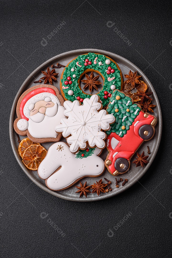 Biscoitos de gengibre frescos e deliciosos de Natal ou ano novo com padrão temático de cor brilhante em fundo escuro de concreto