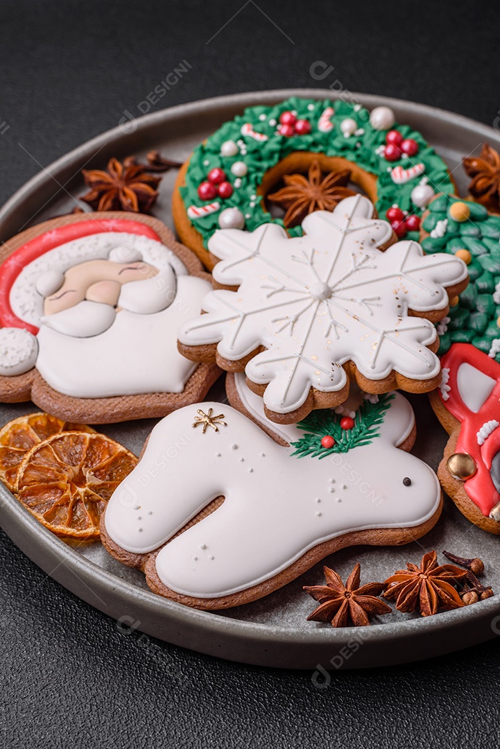 Biscoitos de gengibre frescos e deliciosos de Natal ou ano novo com padrão temático de cor brilhante em fundo escuro de concreto