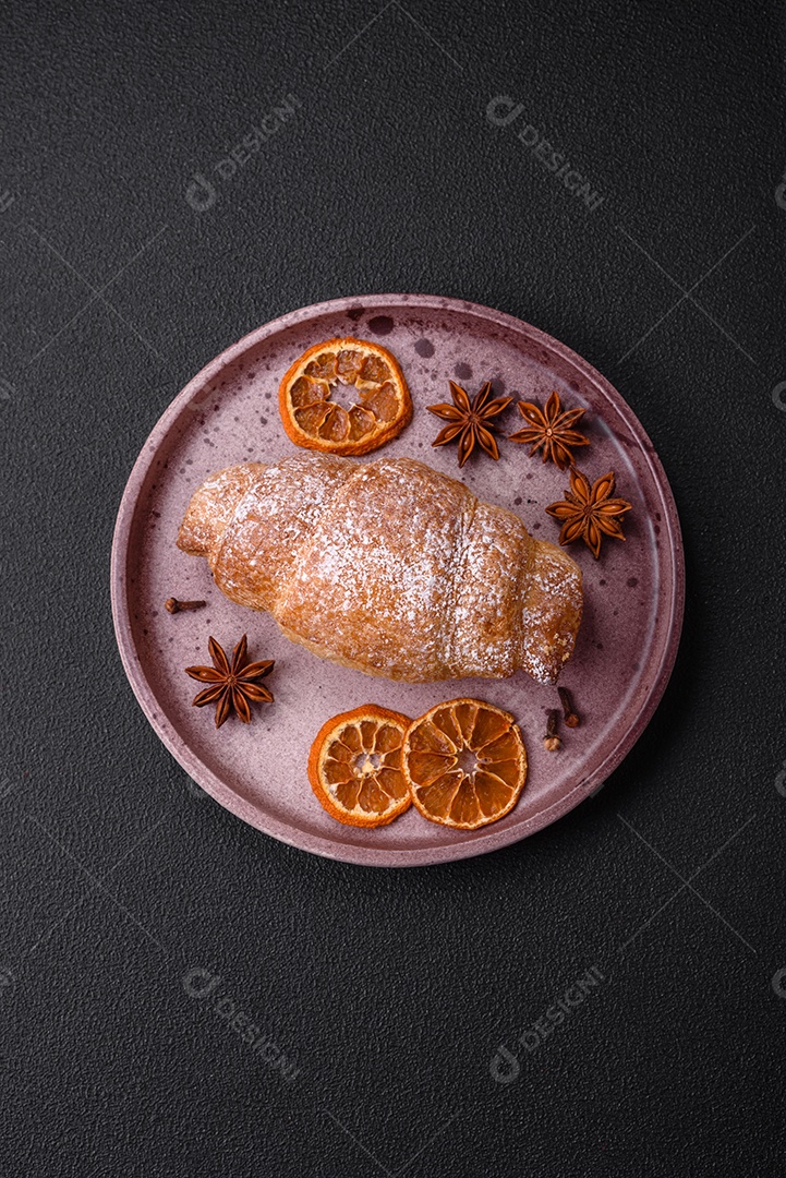 Deliciosos croissants crocantes e frescos com creme de chocolate em uma placa de cerâmica sobre um fundo escuro de concreto