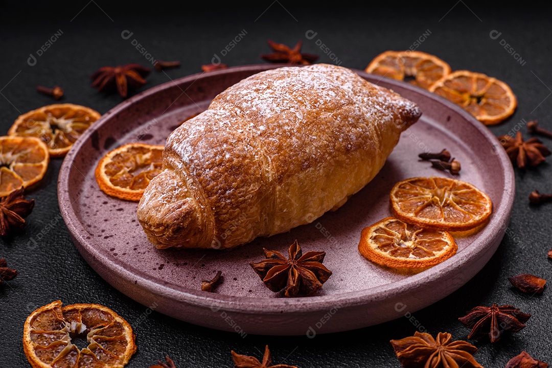 Deliciosos croissants crocantes e frescos com creme de chocolate em uma placa de cerâmica sobre um fundo escuro de concreto