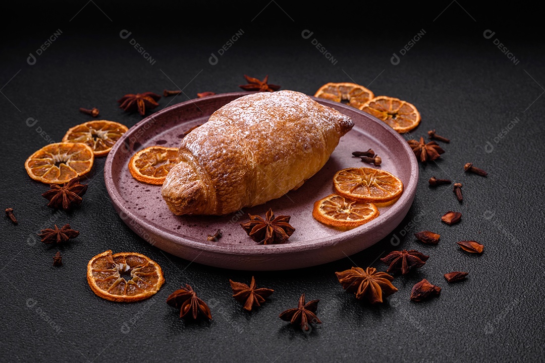 Deliciosos croissants crocantes e frescos com creme de chocolate em uma placa de cerâmica sobre um fundo escuro de concreto