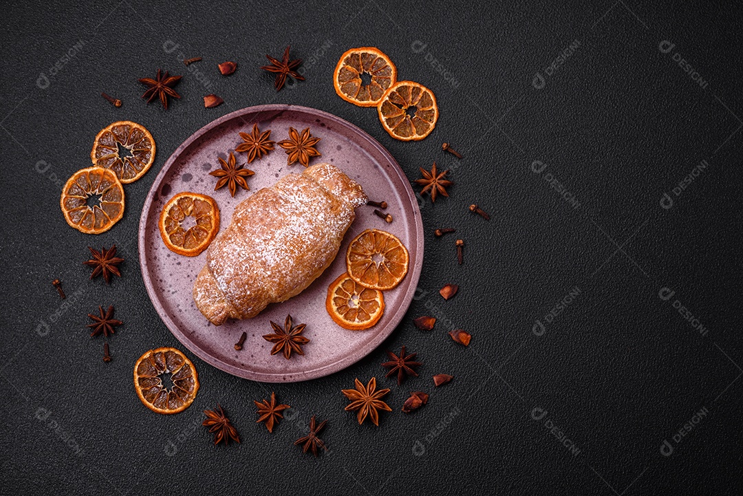 Deliciosos croissants crocantes e frescos com creme de chocolate em uma placa de cerâmica sobre um fundo escuro de concreto