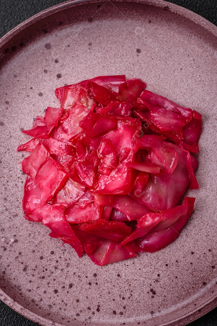 Delicioso repolho rosa picante cortado e cozido em estilo coreano em uma placa cerâmica sobre um fundo escuro de concreto