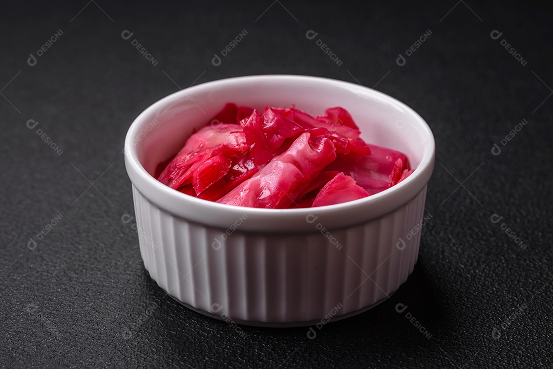 Delicioso repolho rosa picante cortado e cozido em estilo coreano em uma placa cerâmica sobre um fundo escuro de concreto