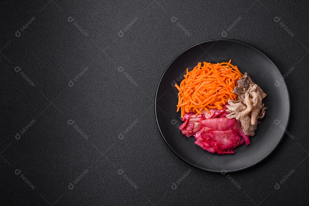 Deliciosos cogumelos picantes, cenouras, repolho fatiado e cozido em estilo coreano em uma placa cerâmica sobre um fundo escuro de concreto