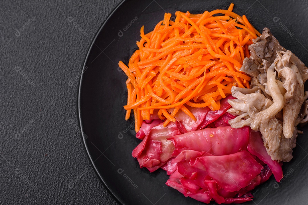 Deliciosos cogumelos picantes, cenouras, repolho fatiado e cozido em estilo coreano em uma placa cerâmica sobre um fundo escuro de concreto