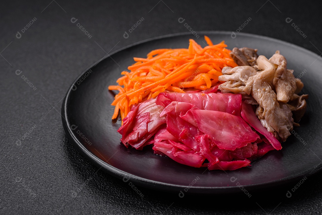 Deliciosos cogumelos picantes, cenouras, repolho fatiado e cozido em estilo coreano em uma placa cerâmica sobre um fundo escuro de concreto