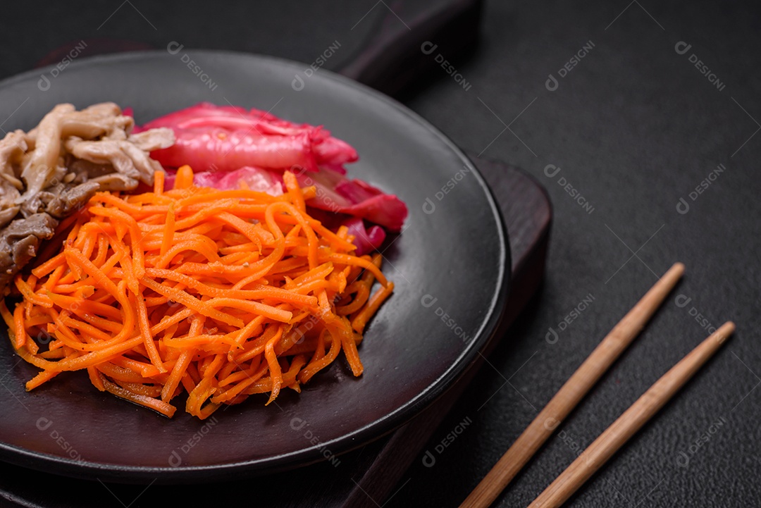 Deliciosos cogumelos picantes, cenouras, repolho fatiado e cozido em estilo coreano em uma placa cerâmica sobre um fundo escuro de concreto