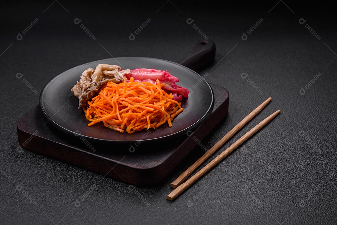 Deliciosos cogumelos picantes, cenouras, repolho fatiado e cozido em estilo coreano em uma placa cerâmica sobre um fundo escuro de concreto