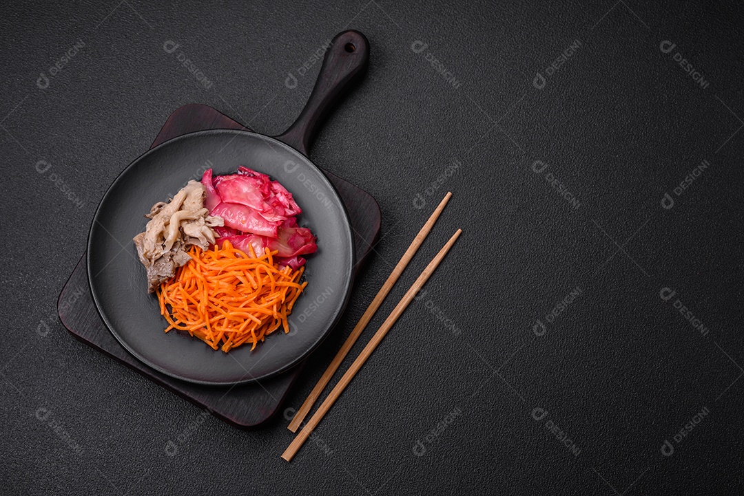 Deliciosos cogumelos picantes, cenouras, repolho fatiado e cozido em estilo coreano em uma placa cerâmica sobre um fundo escuro de concreto