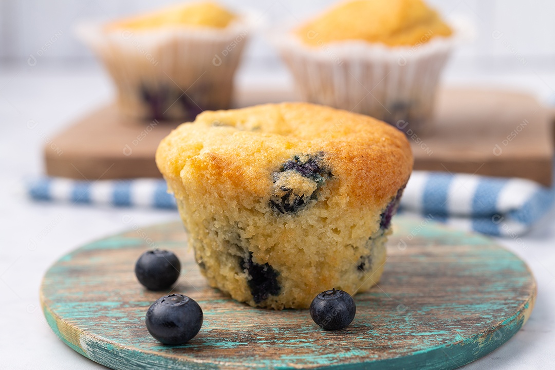 Muffins de mirtilo com frutas sobre tábua de madeira.