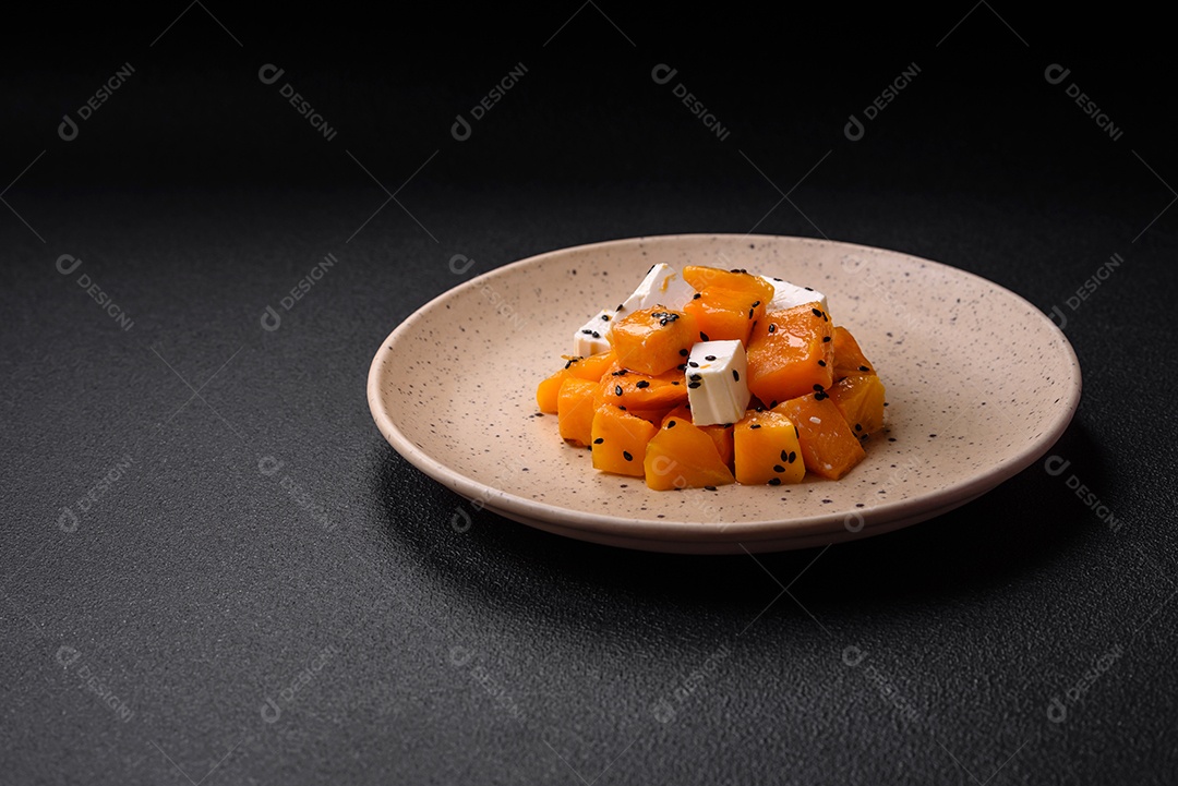 Deliciosa salada suculenta de abóbora grelhada em cubos com queijo feta, especiarias e sementes de gergelim num prato cerâmico