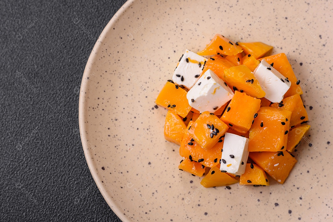 Deliciosa salada suculenta de abóbora grelhada em cubos com queijo feta, especiarias e sementes de gergelim num prato cerâmico