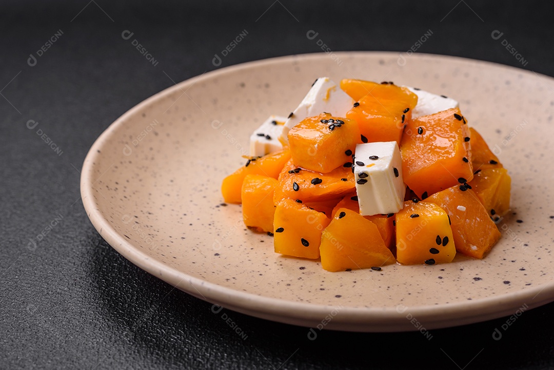 Deliciosa salada suculenta de abóbora grelhada em cubos com queijo feta, especiarias e sementes de gergelim num prato cerâmico