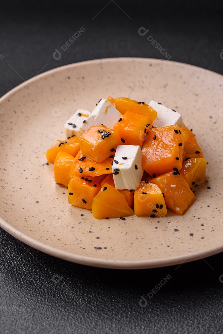 Deliciosa salada suculenta de abóbora grelhada em cubos com queijo feta, especiarias e sementes de gergelim num prato cerâmico