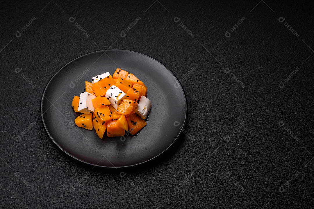 Deliciosa salada suculenta de abóbora grelhada em cubos com queijo feta, especiarias e sementes de gergelim num prato cerâmico