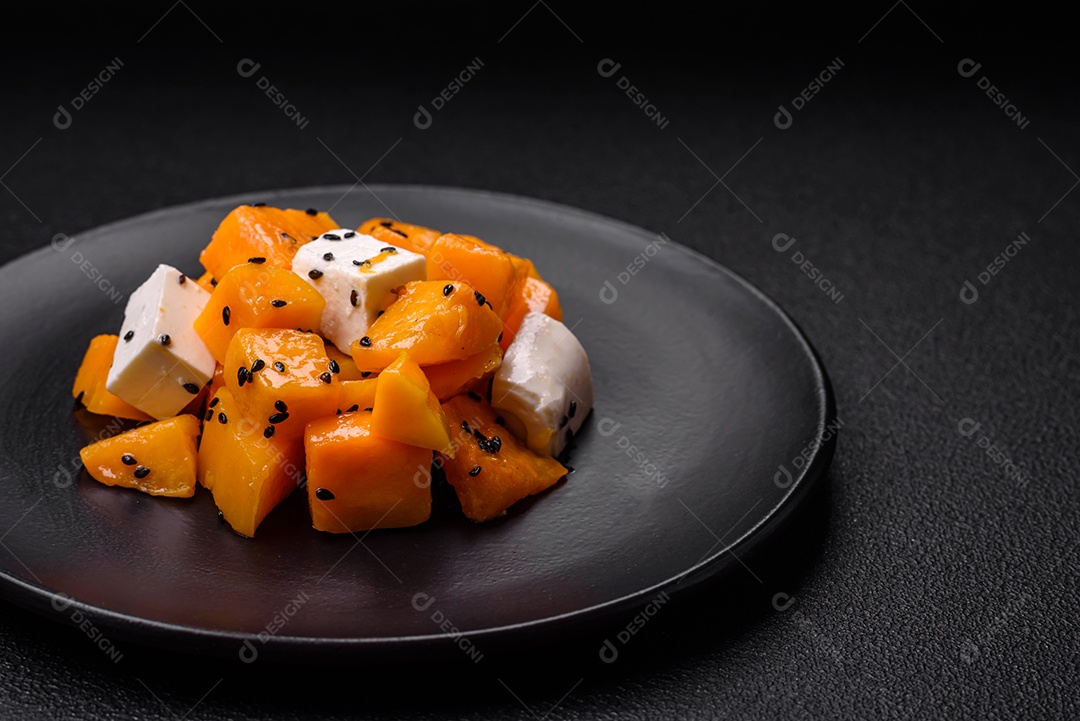 Deliciosa salada suculenta de abóbora grelhada em cubos com queijo feta, especiarias e sementes de gergelim num prato cerâmico