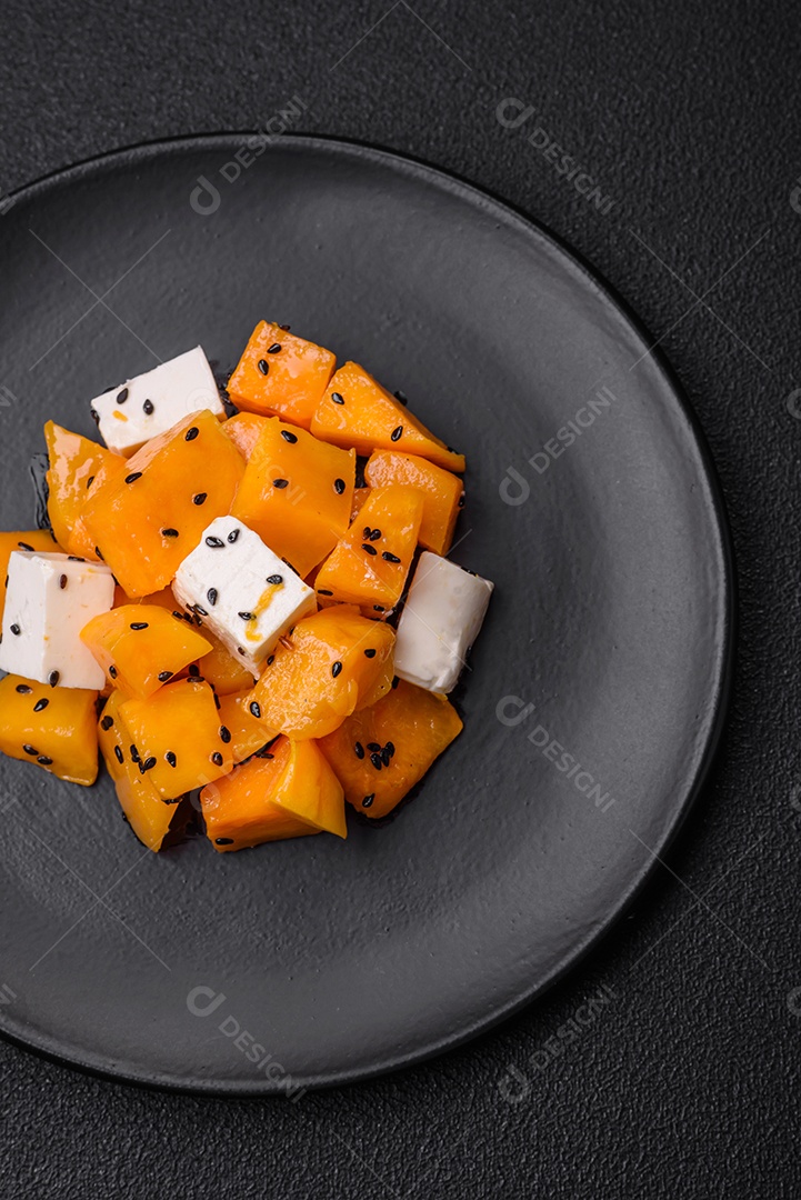 Deliciosa salada suculenta de abóbora grelhada em cubos com queijo feta, especiarias e sementes de gergelim num prato cerâmico