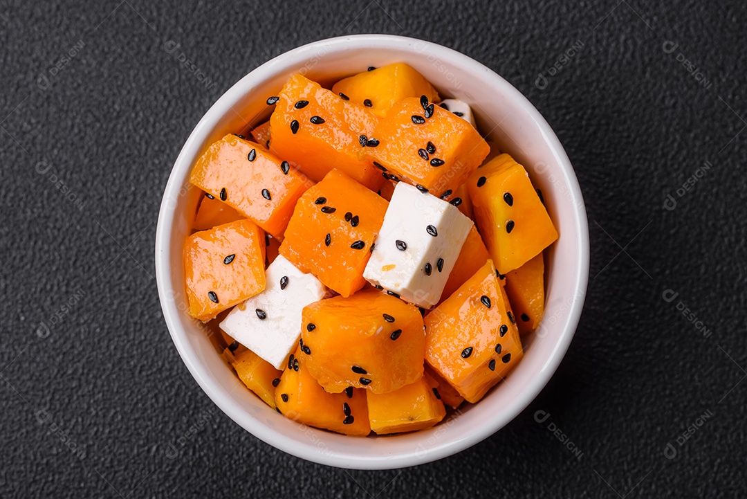 Deliciosa salada suculenta de abóbora grelhada em cubos com queijo feta, especiarias e sementes de gergelim num prato cerâmico
