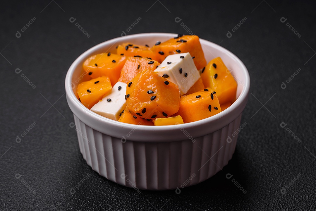 Deliciosa salada suculenta de abóbora grelhada em cubos com queijo feta, especiarias e sementes de gergelim num prato cerâmico