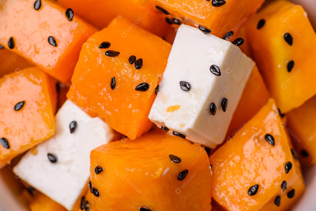 Deliciosa salada suculenta de abóbora grelhada em cubos com queijo feta, especiarias e sementes de gergelim num prato cerâmico