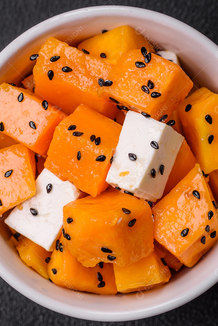 Deliciosa salada suculenta de abóbora grelhada em cubos com queijo feta, especiarias e sementes de gergelim num prato cerâmico