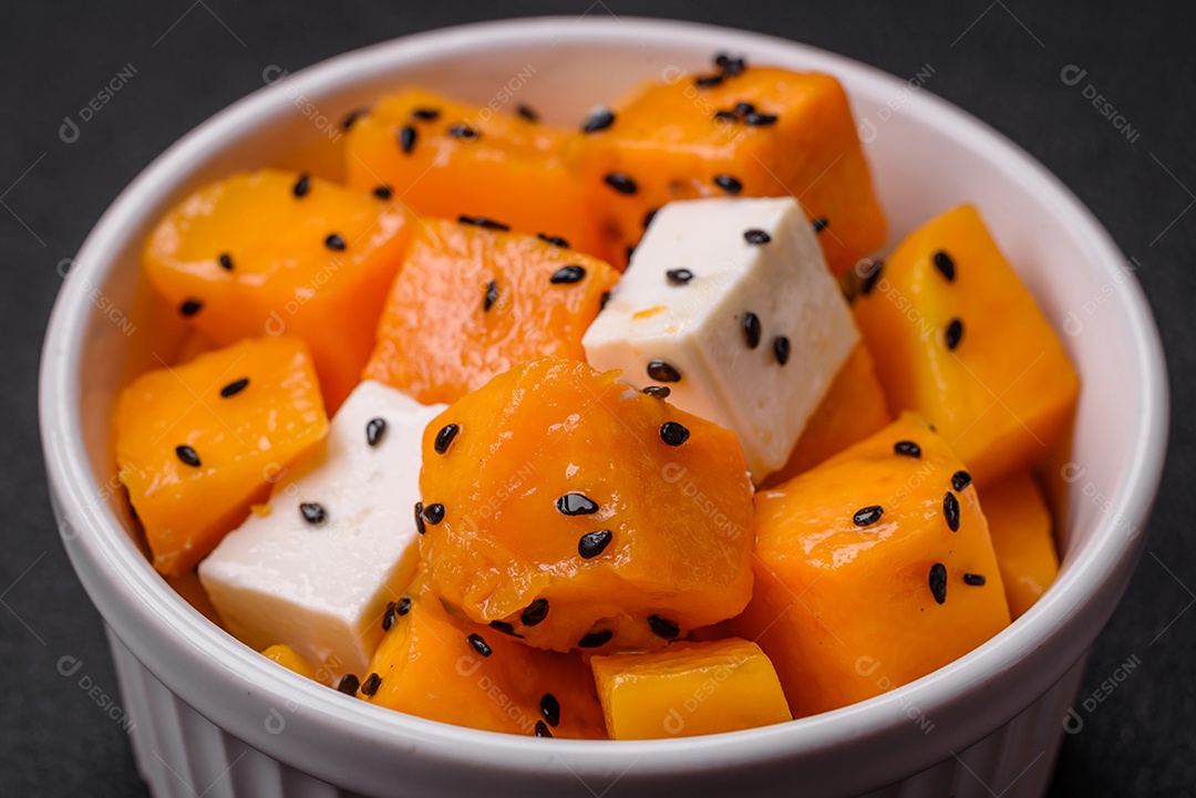 Deliciosa salada suculenta de abóbora grelhada em cubos com queijo feta, especiarias e sementes de gergelim num prato cerâmico