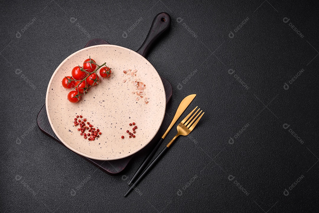 Prato cerâmico vazio em um fundo escuro texturizado. Preparando utensílios de cozinha para um jantar em família