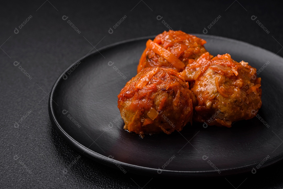 Deliciosas almôndegas frescas de carne picada ou peixe com molho de tomate, cenoura, cebola, sal e especiarias sobre um fundo escuro de concreto