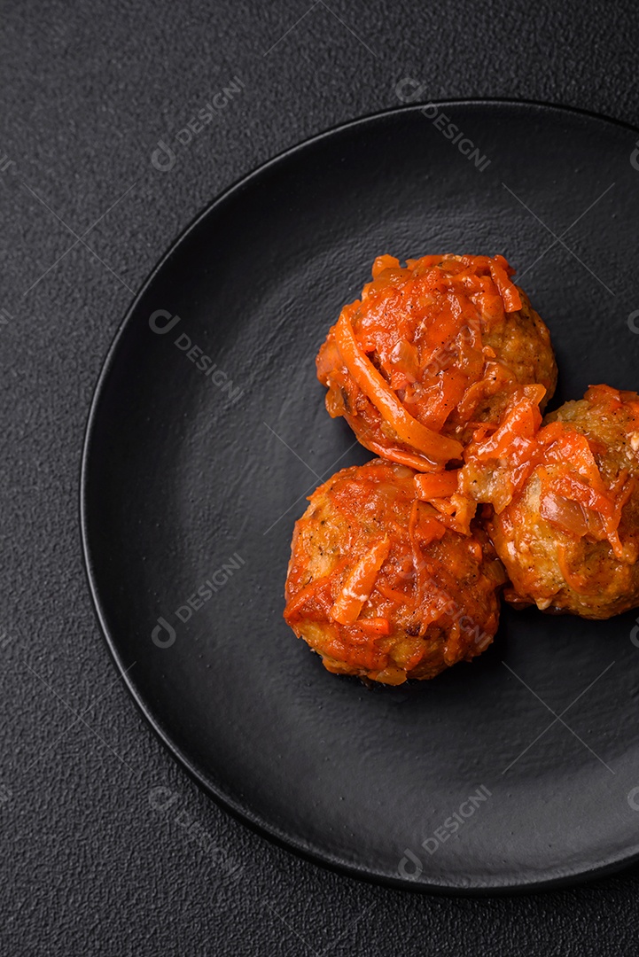 Deliciosas almôndegas frescas de carne picada ou peixe com molho de tomate, cenoura, cebola, sal e especiarias sobre um fundo escuro de concreto