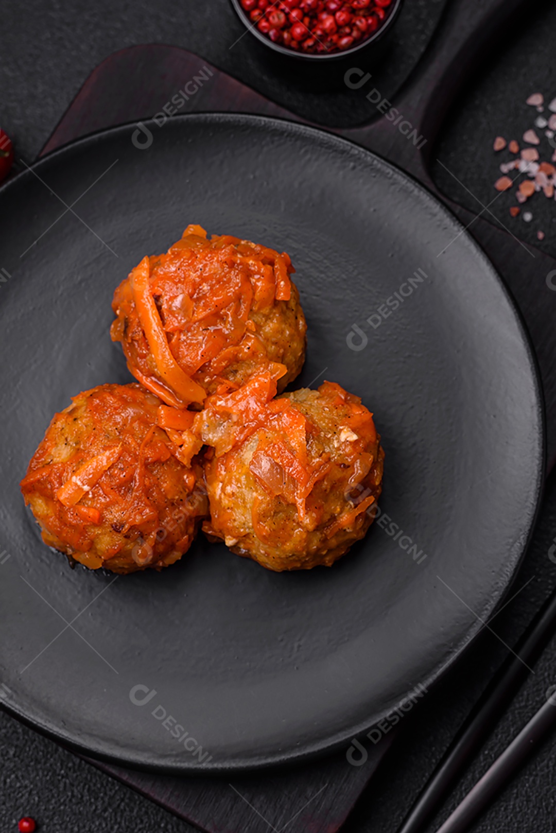 Deliciosas almôndegas frescas de carne picada ou peixe com molho de tomate, cenoura, cebola, sal e especiarias sobre um fundo escuro de concreto