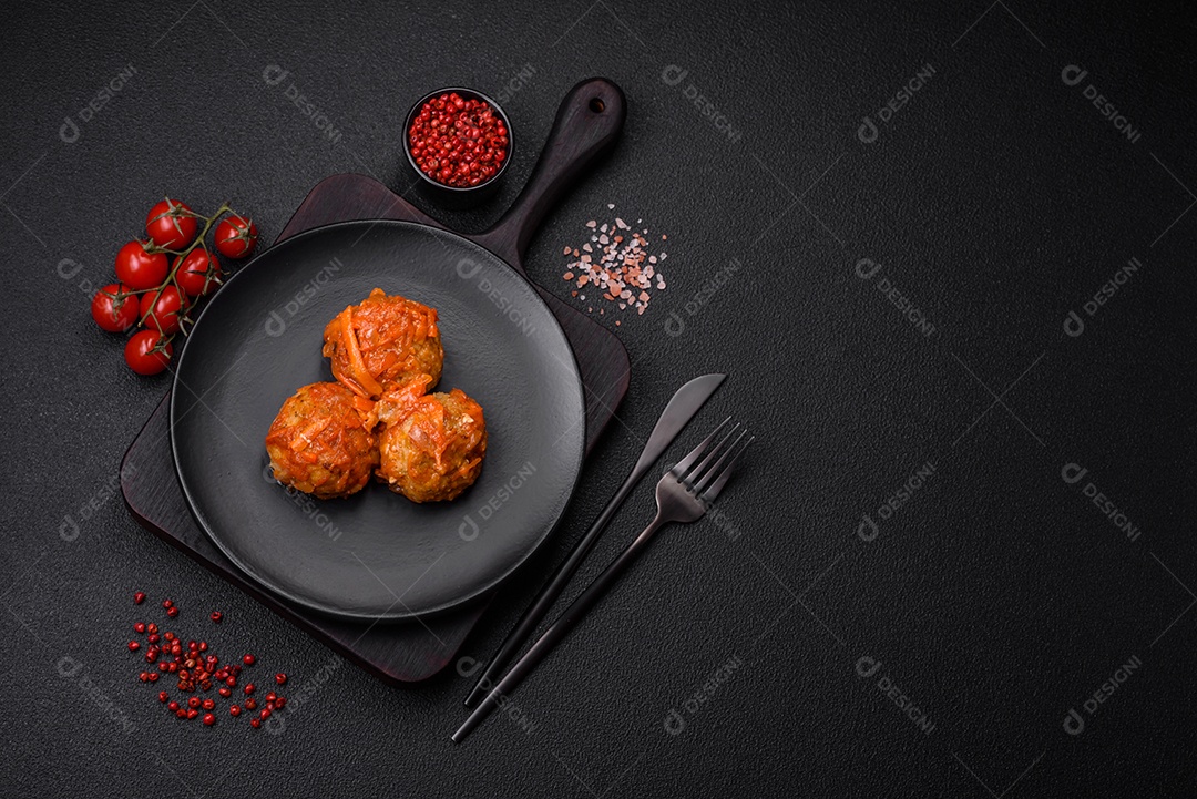 Deliciosas almôndegas frescas de carne picada ou peixe com molho de tomate, cenoura, cebola, sal e especiarias sobre um fundo escuro de concreto