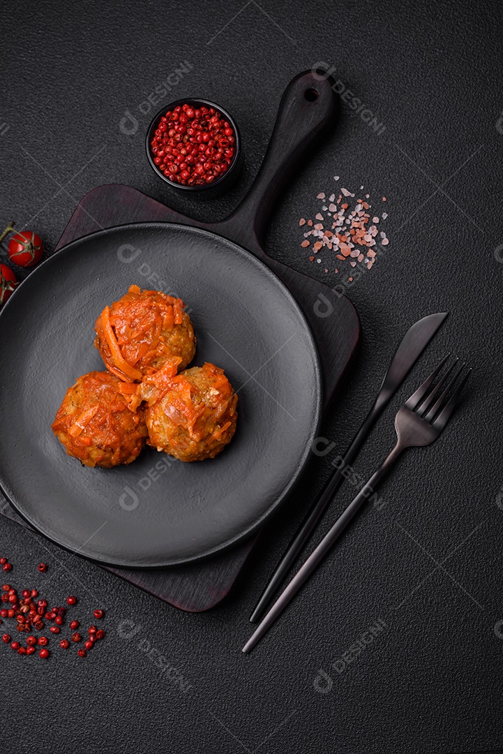 Deliciosas almôndegas frescas de carne picada ou peixe com molho de tomate, cenoura, cebola, sal e especiarias sobre um fundo escuro de concreto