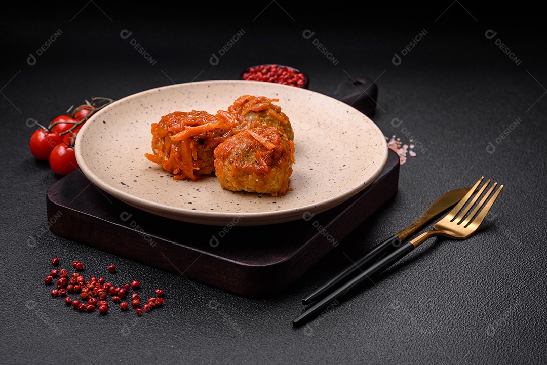 Deliciosas almôndegas frescas de carne picada ou peixe com molho de tomate, cenoura, cebola, sal e especiarias sobre um fundo escuro de concreto