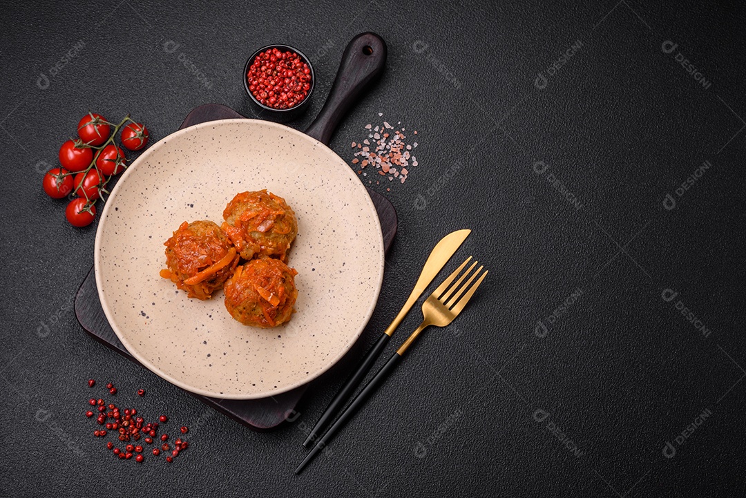 Deliciosas almôndegas frescas de carne picada ou peixe com molho de tomate, cenoura, cebola, sal e especiarias sobre um fundo escuro de concreto
