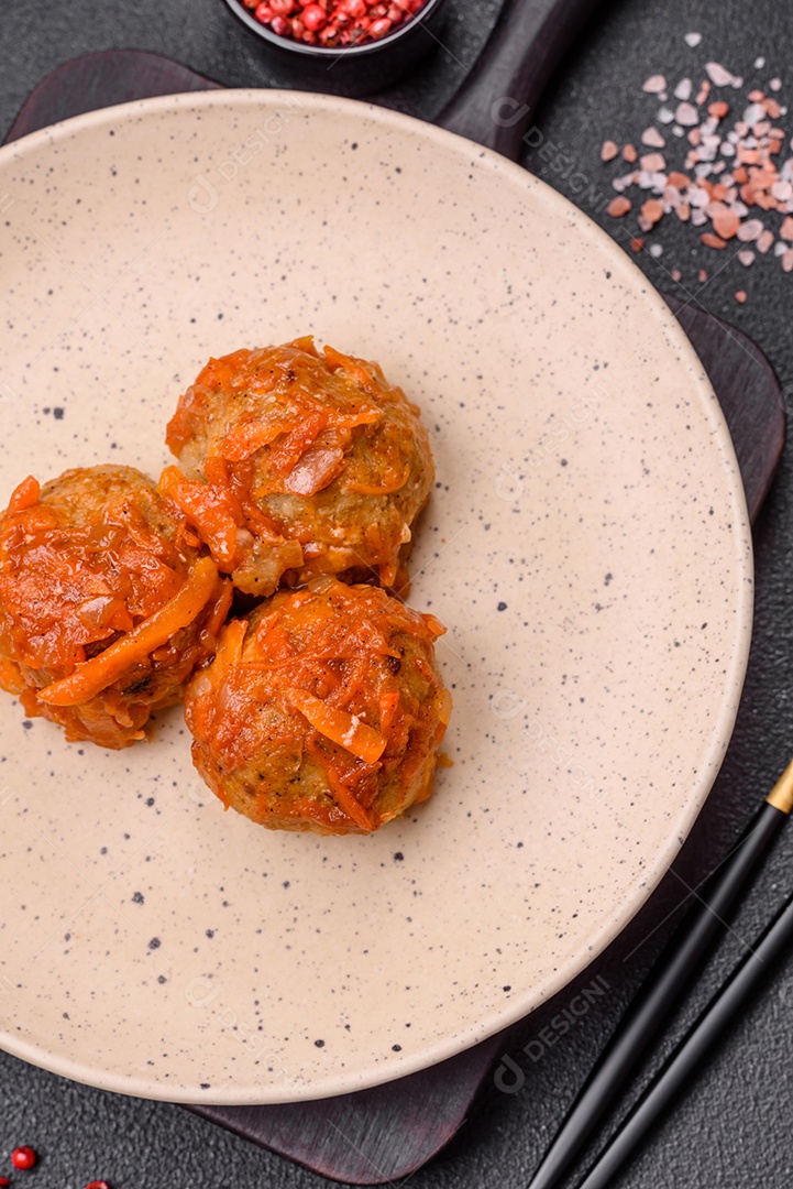 Deliciosas almôndegas frescas de carne picada ou peixe com molho de tomate, cenoura, cebola, sal e especiarias sobre um fundo escuro de concreto