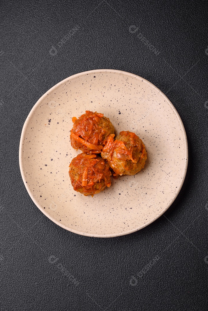 Deliciosas almôndegas frescas de carne picada ou peixe com molho de tomate, cenoura, cebola, sal e especiarias sobre um fundo escuro de concreto