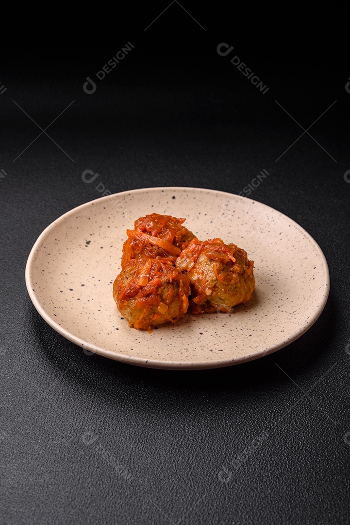 Deliciosas almôndegas frescas de carne picada ou peixe com molho de tomate, cenoura, cebola, sal e especiarias sobre um fundo escuro de concreto