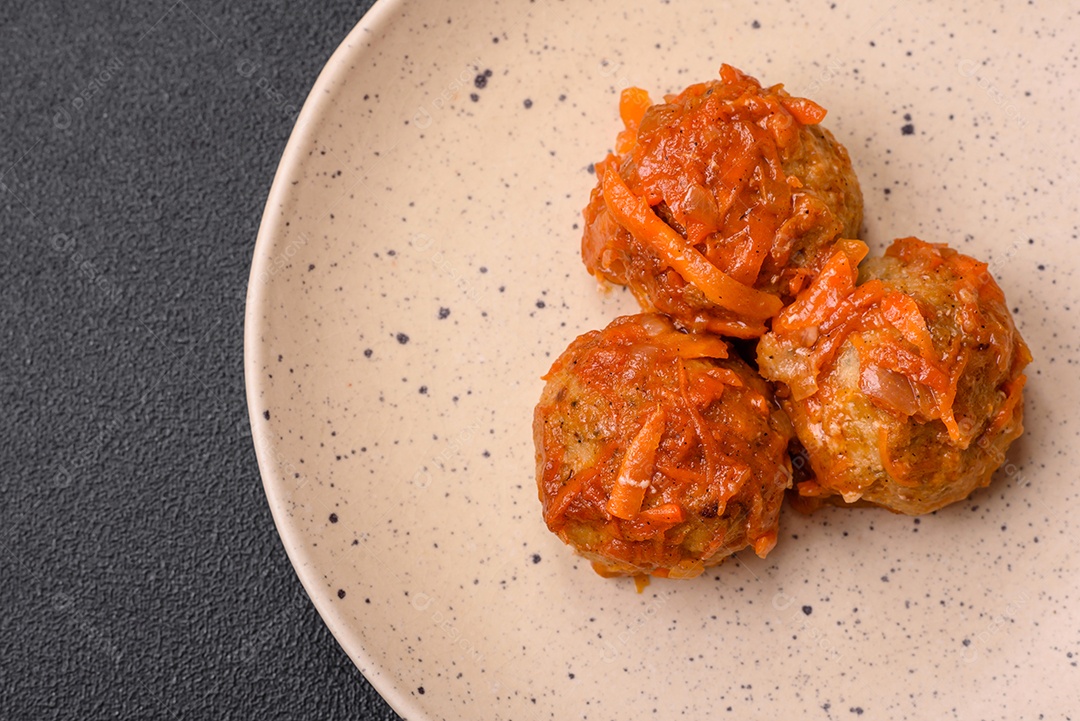 Deliciosas almôndegas frescas de carne picada ou peixe com molho de tomate, cenoura, cebola, sal e especiarias sobre um fundo escuro de concreto