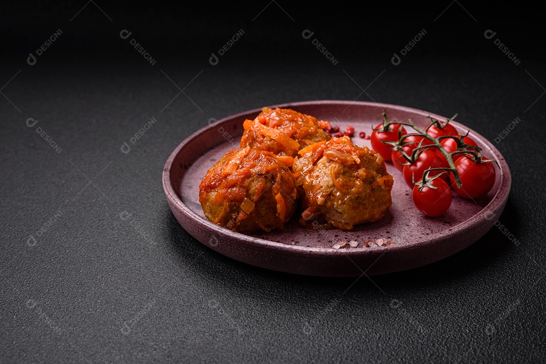 Deliciosas almôndegas frescas de carne picada ou peixe com molho de tomate, cenoura, cebola, sal e especiarias sobre um fundo escuro de concreto