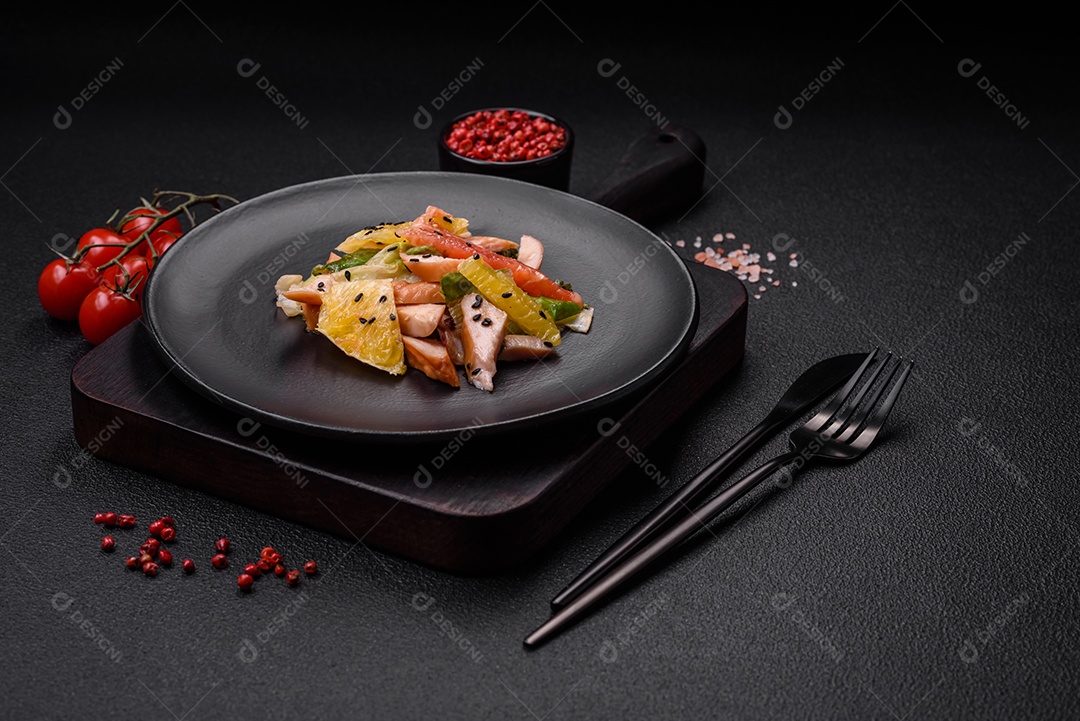 Deliciosa salada fresca e suculenta de frango fatiado, toranja, alface, gergelim com azeite em uma placa cerâmica sobre um fundo de concreto