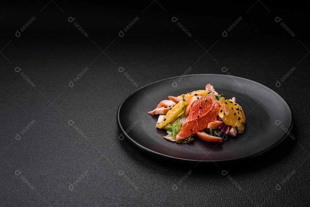 Deliciosa salada fresca e suculenta de frango fatiado, toranja, alface, gergelim com azeite em uma placa cerâmica sobre um fundo de concreto