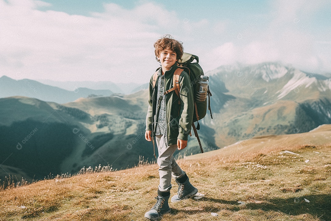 Menino andando no topo da montanha com mochila sorrindo para a câmera