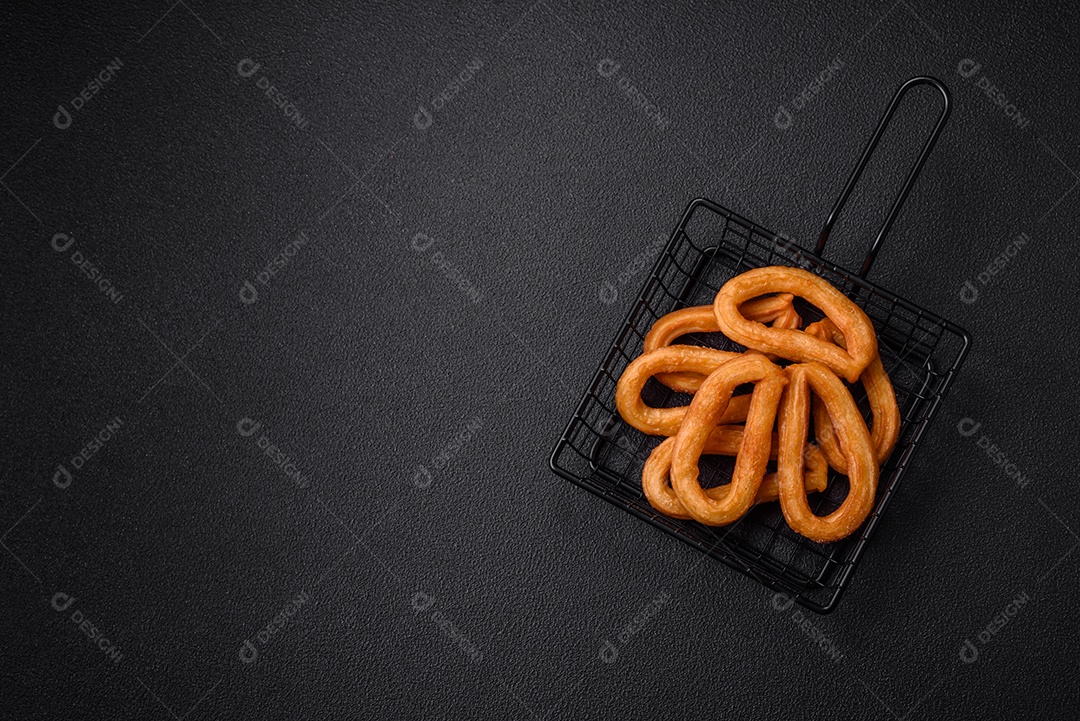 Deliciosos churos doces com açúcar de confeiteiro e creme dentro sobre um fundo escuro de concreto. Prato de fast-food